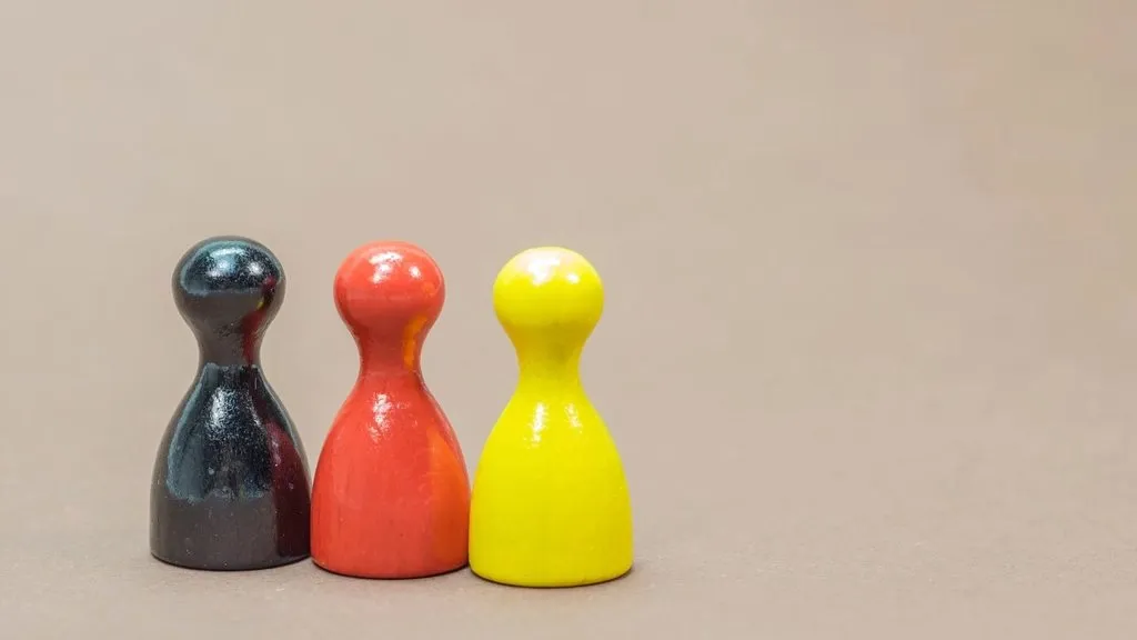 Three board-game pawns in black, red and yellow