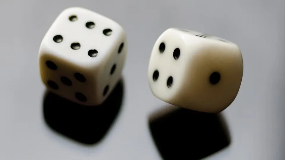 Two white dice on a reflective surface
